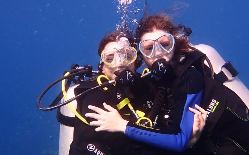 Two friends embrace while scuba diving on Broadreach summer camp